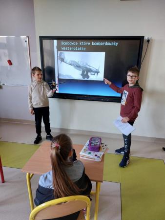 Uczniowie klasy 3b prowadzą lekcje historii przy tablicy multimedialnej w sali lekcyjnej.