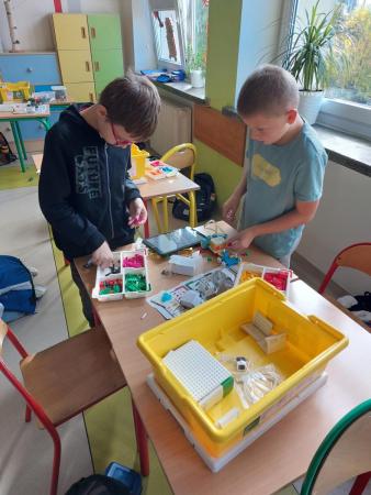 Uczniowie w sali lekcyjnej budują pojazd z klocków LEGO