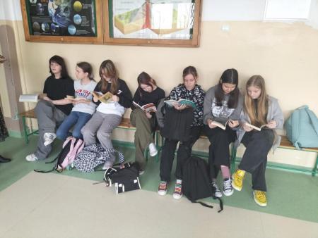 Uczniowie czytający ksiązki na korytarzu szkolnym