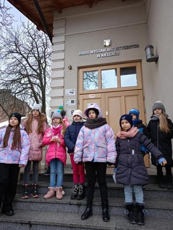 Uczniowie świetlicy szkolnej pozują do zdjęcia przed wejściem do BWA w Kielcach.