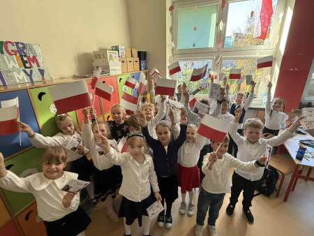 Uczniowie w klasie z białoczerownymi flagami