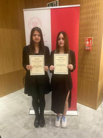 Uczennice sp12 z dyplomami na tle flagi Polski