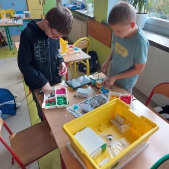 Uczniowie w sali lekcyjnej budują pojazd z klocków LEGO