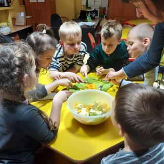 Uczniowie i nauczyciel w trakcie przygotowywania sałatki owocowej na zajęciach świetlicowych