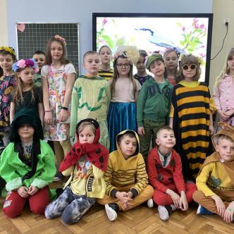 Uczniowie i wychowawca klasy 1a pozują do zdjęcia w strojach z okazji pierwszego dnia wiosny