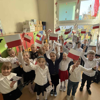 Uczniowie w klasie z białoczerownymi flagami