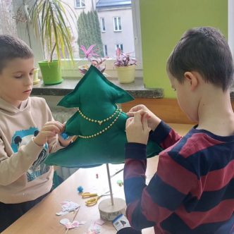 uczniowie szyjący choinkę